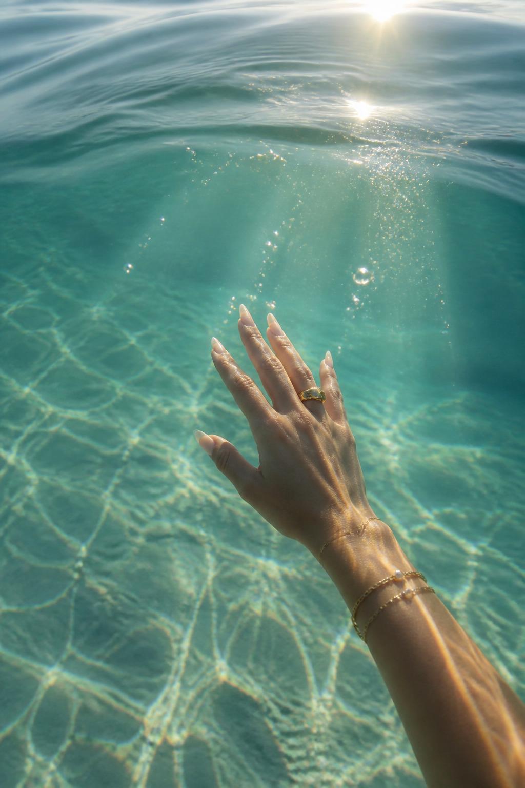 A hand reaching up through deep glowing water — someone offering connection